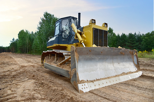 Dozer during clearing forest for construction new road. Yellow Bulldozer at forestry work Earth-moving equipment at road work, land clearing, grading, pool excavation, utility trenching