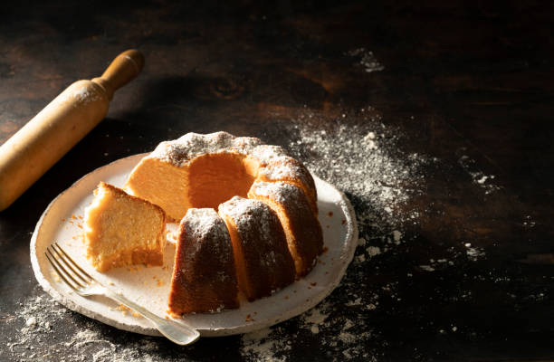 Bundt cake made of tangerine clementines baked homemade Bundt cake made of tangerine clementines baked homemade with fork and rolling pin on moody dark background pound cake stock pictures, royalty-free photos & images