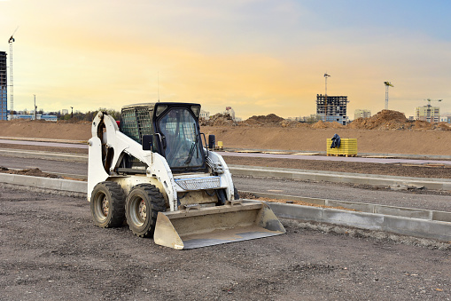 Skid-steer loader for loading and unloading works on city streets. ompact construction equipment for work in limited conditions. Road repair at construction site