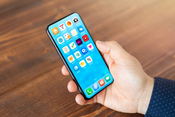 istock Man holding mobile phone with different everyday application icons on home screen 1297012981