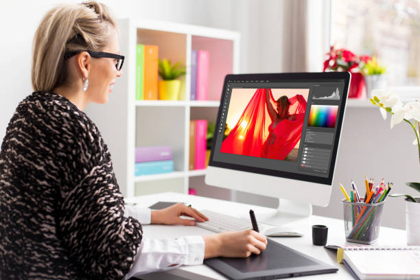 Woman editing photo on computer Woman editing photo on computer. Software interface is completely made up. design professional photos stock pictures, royalty-free photos & images