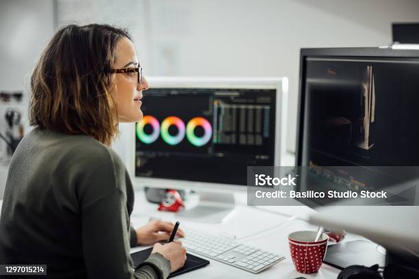 Female Graphic Designer At Desk In The Office With Two Displays Stock Photo - Download Image Now
