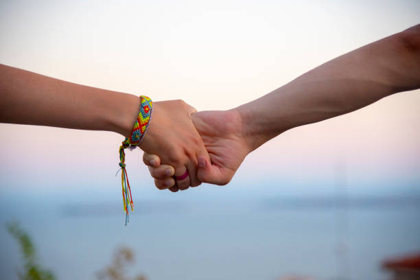 istock Two hands, male and female, holding each other tightly, on a blurred light background. 1297016124