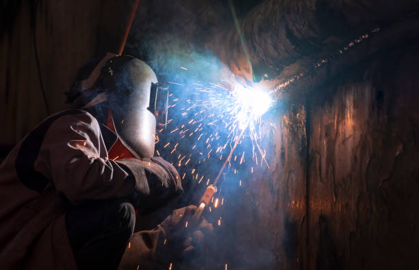 soldador en máscara de soldadura está soldando la pared de metal del viejo buque de pesca en el astillero en estilo tono oscuro - industrial ship flash fotografías e imágenes de stock