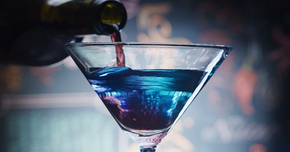 Mixing red and blue cocktail in martini glass