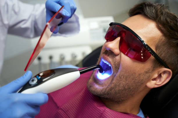 istock Young man at dental appointment having treatment with blue light 1297017901