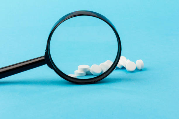istock Concept - pharmaceutical testing, testing of medicines, magnifying glass, tablets on a blue background. Doping control. 1297018119