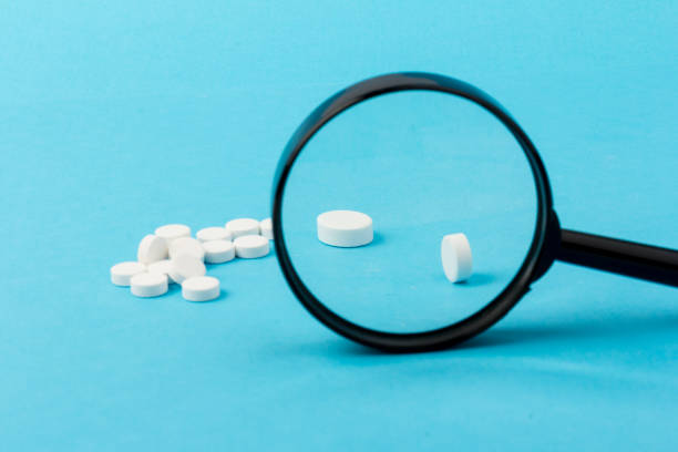 istock Concept - pharmaceutical testing, testing of medicines, magnifying glass, tablets on a blue background. Doping control. 1297018306