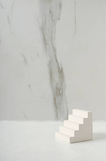 istock Vertical image of white decorative stairs as a podium on the white surface against white marble wall 1297018488