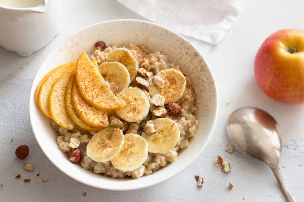 istock Oatmeal with banana, apple, nuts and cinnamon on a light gray background 1297019059