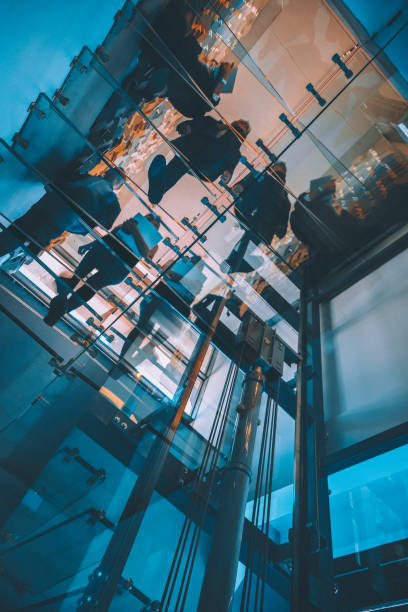 Motion blur of people walking on transparent glass spiral staircase in futuristic building on a contemporary office