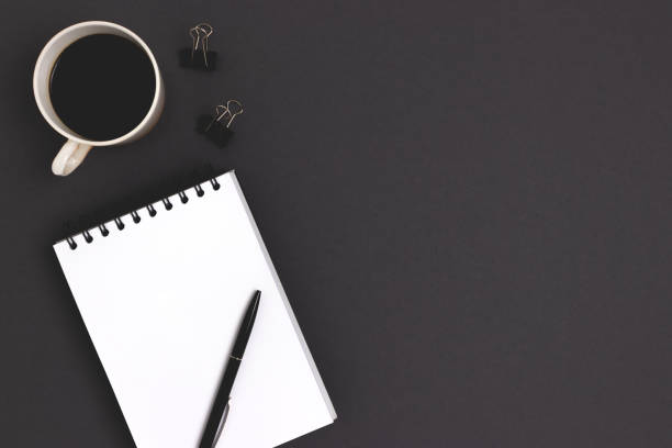 istock Workspace with notepad mockup, stationery and coffee cup on a black background. 1297019571