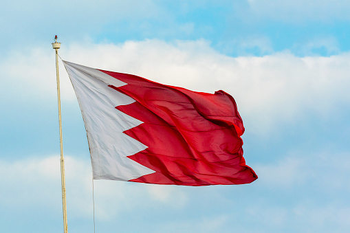 Blue sky and mast with hanged waving flag of Bahrain