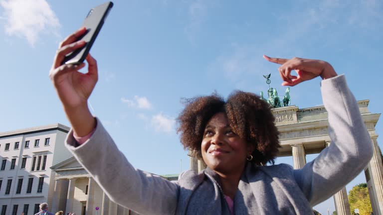 Woman taking selfie in front of Brandenburg gate in Berlin