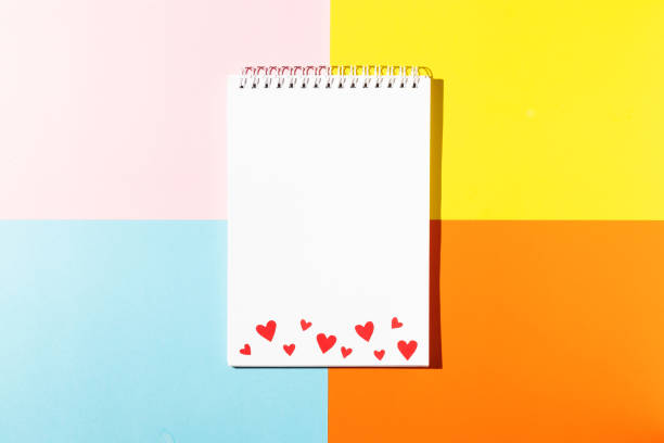 istock White notepad with red cardboard hearts on pink yellow blue and orange background copy space 1297024356