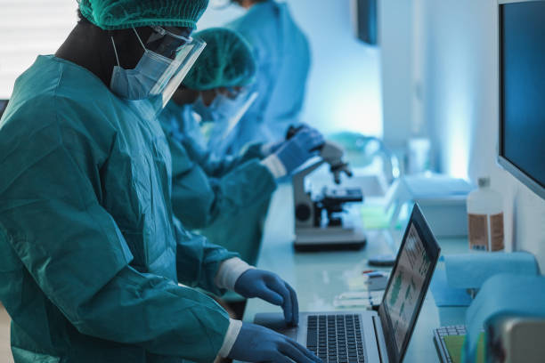 istock Medical workers in hazmat suit working with laptop computer and micoroscope inside laboratory hospital during coronavirus outbreak - Focus on african man face 1297025228