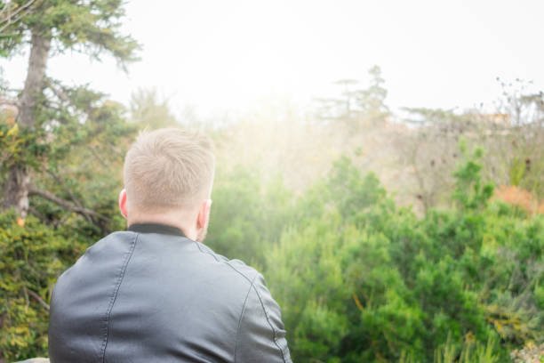 istock young man from behind looking at light in the sky. Motivation and religion concept 1297026757