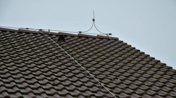 an earth wire must be installed on each gray roof, which copies the outline of the building and protects the truss from being struck by lightning architecture, bone, bones, brake, building, children, climb, conductor, dangerous, delivers, distance, down, earth, electric, electricity, electronics, exterior, fall, falling, forbidden, gray, ground, home, house, installation, ladder, legs, lightning, outline, point, protection, rob, roof, safety, shock, silhouette, sky, slate, sleep, storm, thief, thunder, thunderbolt, tiles, top, touch, window, wire, burnt, tiles, tile, gray, zinc, ridge slate ridge stock pictures, royalty-free photos & images