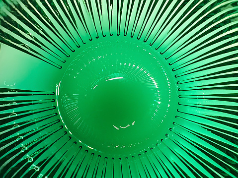 Disparo de fondo borroso abstracto a través de vidrio verde grueso con rayos brillantes. Telón de fondo de colores difusos. Fondo de botella de vidrio. photo