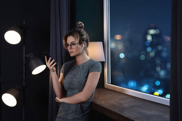 istock Businesswoman using wireless earbuds and smartphone during late night work 1297032234