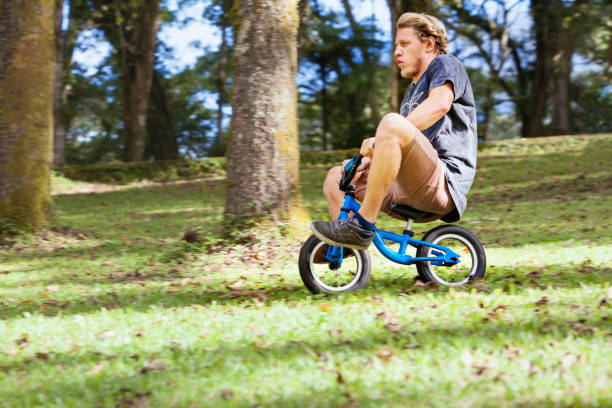Funny downhill on small kids balance bike. Funny downhill on small kids balance bike. Young crazy man riding down from high hill. clown photos stock pictures, royalty-free photos & images