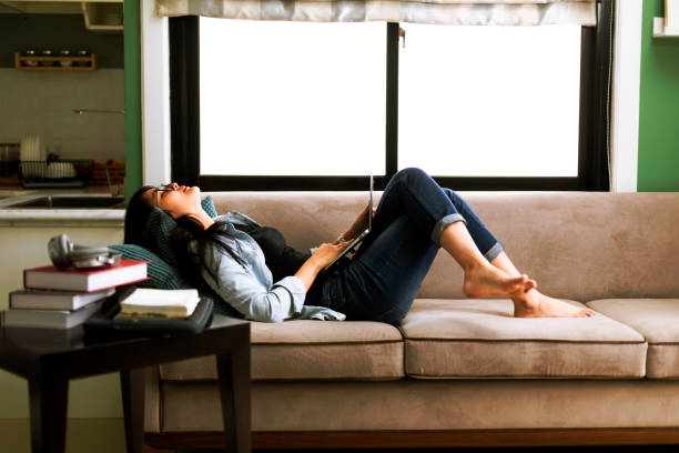 istock asian young woman lay down on couch using laptop working at home 1297033809