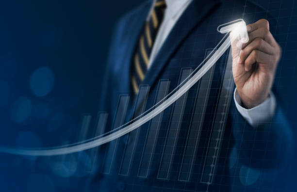 Business growth, boost up business, progress in business or success concept. Businessman is drawing exponential growth graph on dark tone background. stock photo