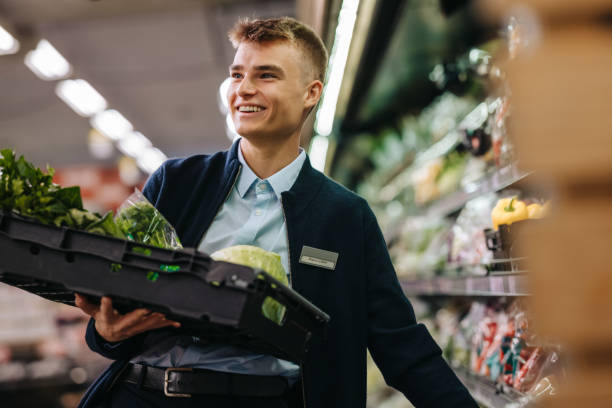 istock Trainee stocking up fresh vegetables on shelf in supermarket 1297037845