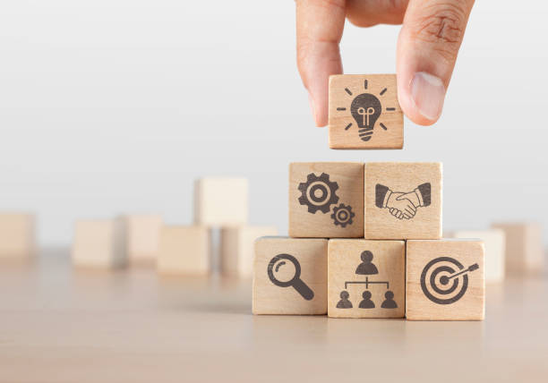 Business strategy, business management or business success concept. Wooden blocks with business icon arranged in pyramid stair shape and a man is holding the top one. stock photo