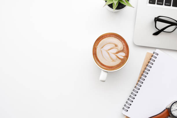 istock White office desk table with blank notebook, laptop computer, cup of coffee and supplies. Top view with copy space, flat lay. 1297039056