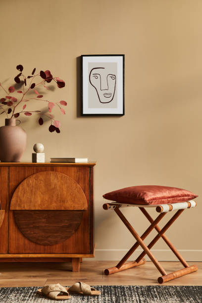 istock Stylish interior with design wooden commode, stool, dried flowers in vase, unique decoration, carpet, mock up poster frame and elegant personal accessories. Modern living room in classic house. 1297039174