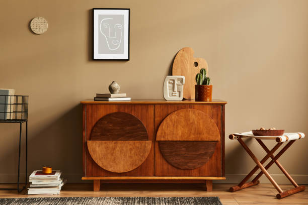 istock Stylish interior with design wooden commode, stool, cacti in pot, unique decoration, carpet, mock up poster frame and elegant personal accessories. Modern living room in classic house. 1297039175