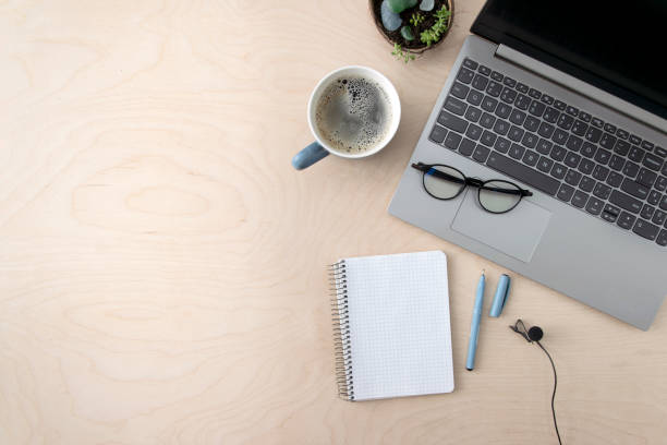istock Freelancer workplace. Laptop, coffee, notepad, microphone for recording lessons on a wooden table, top view. Online learning concept, recording podcasts. 1297040928