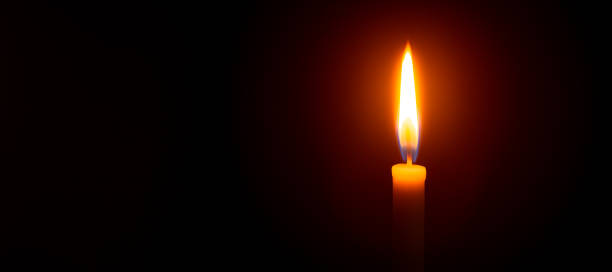 istock Close up single candle light and flame on black background 1297041150