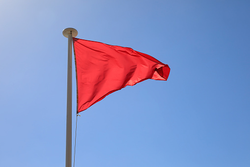 The red triangular flag is placed on top of the mast for warning purposes.
