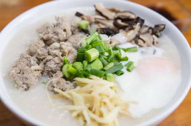 Pork porridge with eggs placed on a wooden table.
