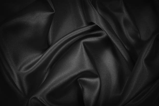 istock Abstract black background. Black silk satin fabric texture background. Beautiful soft folds on shiny fabric. Black elegant background for your design. 1297047221