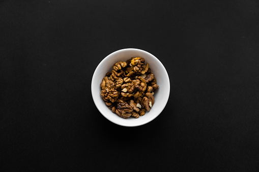 Walnut in a small plate on a black table. Walnuts is a healthy vegetarian protein nutritious food. Natural nuts snacks