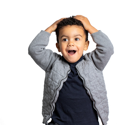 Close up studio portrait of funny afro american boy with hands on head. Kid with surprised facial expression and open mouth Isolated on white background.