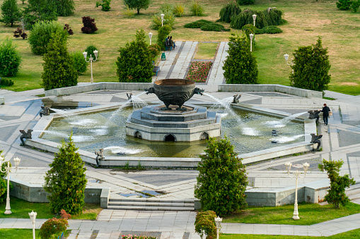 Streams of fountain water with sculpture statue with sun. Close-up of Garden waterfall in pond. Outdoor garden park. Relaxation.