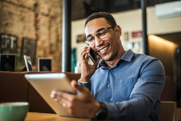 giovane uomo d'affari che utilizza un tablet digitale in un ufficio moderno - businessman men business person smiling foto e immagini stock