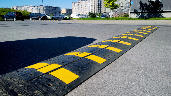 St. Petersburg, Russia - August 9, 2020: Speed bump near apartment building and school. Sleeping policeman. Road safety regulations. Traffic rules concept. Car parking. Real city life. Tarmac. Shadow.