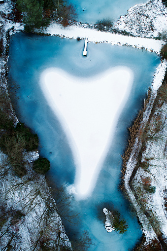 Frozen fishpond with a heart-shaped snow surface - aerial view