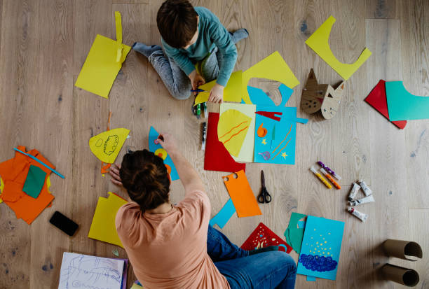 istock Mother and kid cutting paper and making collages 1297053102
