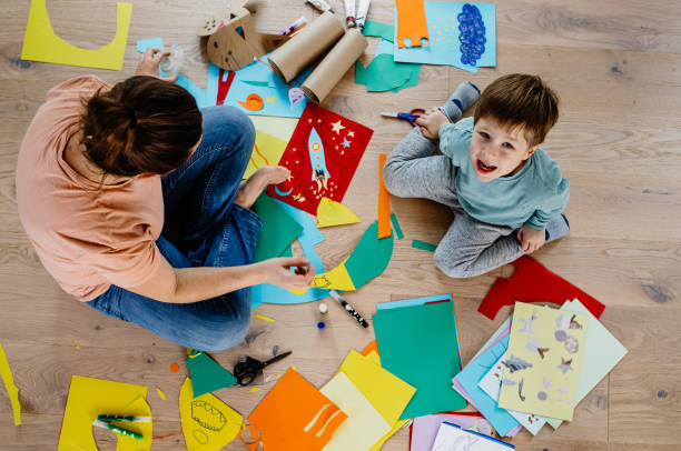 istock Mother and kid cutting paper and making collages 1297053103