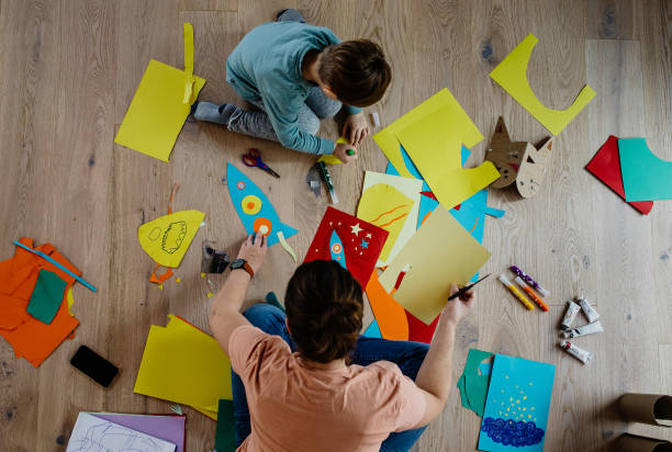 Mother and kid cutting paper and making collages