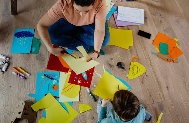 istock Mother and kid cutting paper and making collages 1297053268