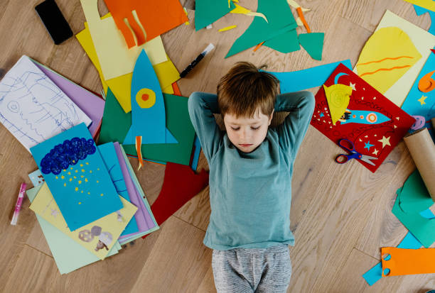 istock Kid lying down on the floor surrounded by cut out collage 1297053283