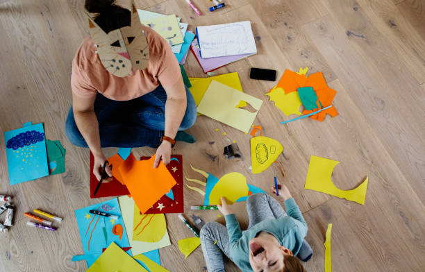 istock Mother and kid cutting paper and making collages 1297053688