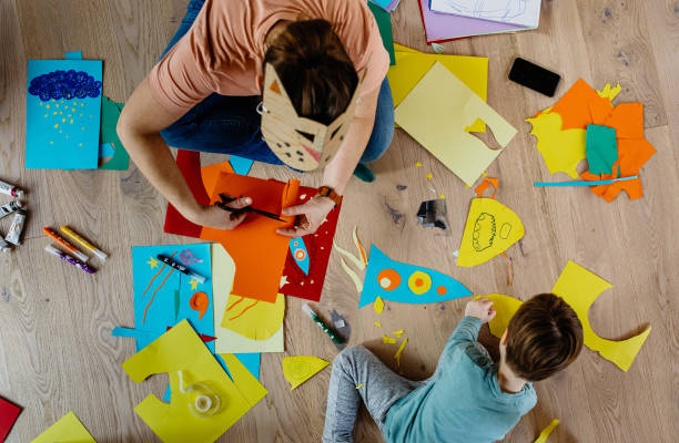 istock Mother and kid cutting paper and making collages 1297053883